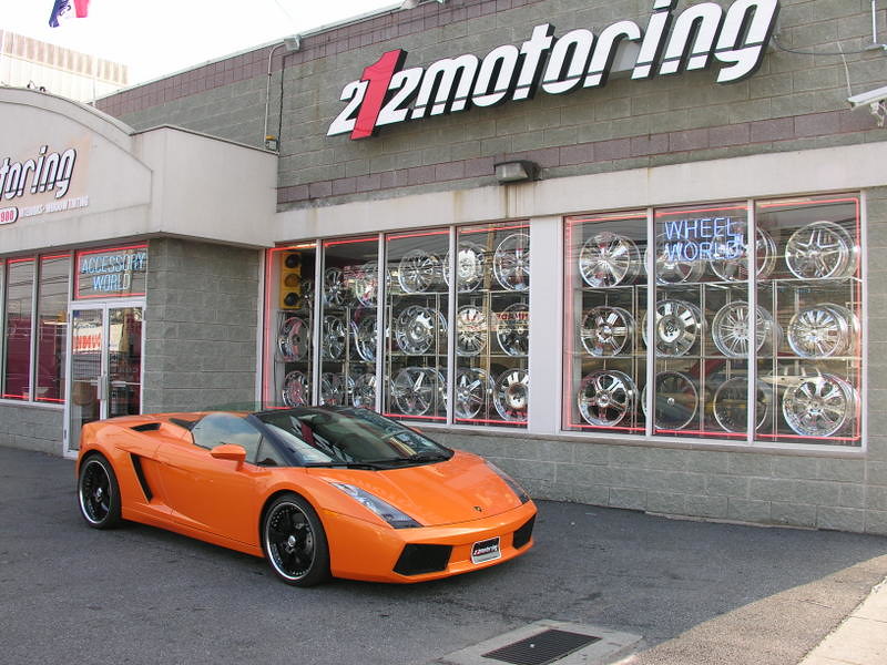 An orange car in front of the 212 Motoring storefront