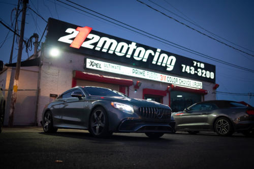 Two cars under the 212 Motoring sign at night
