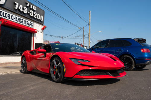 A red Ferrari in front of the 212 Motoring garage